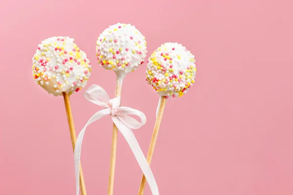 Pastel pops decorado con aspersiones sobre fondo rosa —  Fotos de Stock
