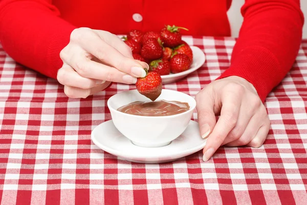 Woman eating chocolate strawberry fondue, sitting by the table — Stock Photo, Image