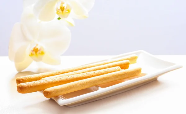 Breadsticks and white orchids on the table — Stock Photo, Image