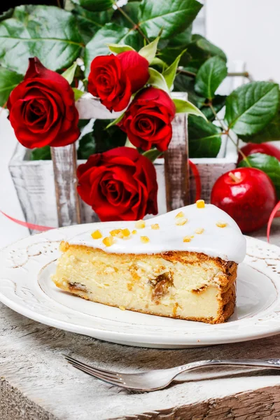 Tarta de queso en plato blanco, rosas rojas en el fondo — Foto de Stock