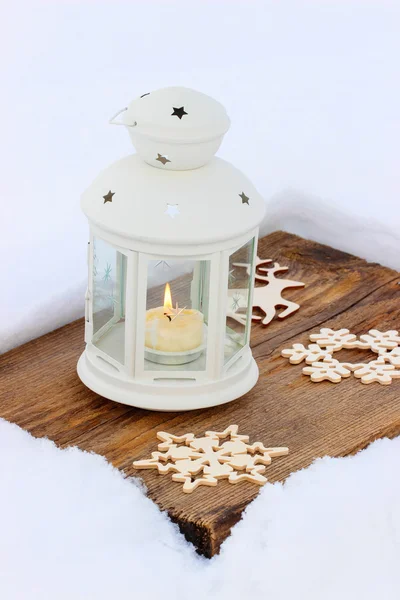 Lanterne blanche debout sur une planche de bois, sur la neige — Photo