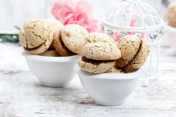 Macaroane pariziene pe masă albă din lemn. Flori de garoafă roz — Fotografie, imagine de stoc