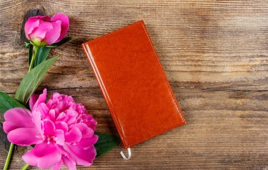 küçük kitap ve gösterişli pembe peonies ahşap masa üstünde. Üstten Görünüm