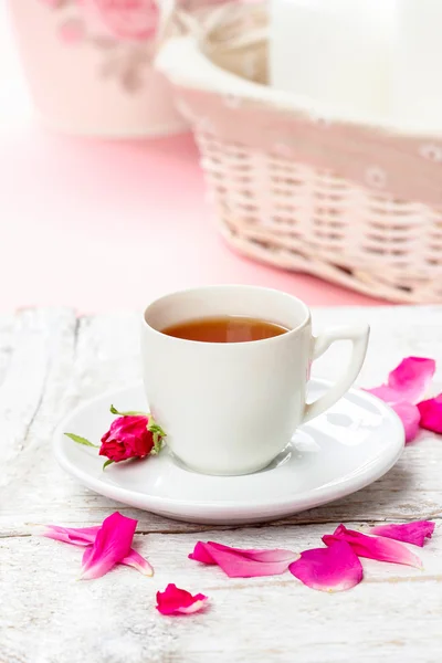 Tasse de thé décorée de pétales de rose dans un décor de table rose — Photo