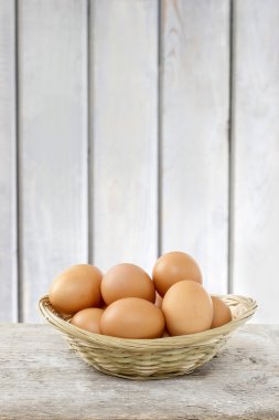 ahşap zemin üzerinde hasır sepet yumurta yığınını. kopya alanı.