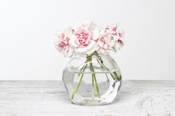 Buquê de cravos rosa em vaso de vidro pequeno . — Fotografia de Stock