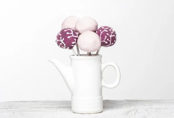 ピンクと紫のケーキを木の背部の白いセラミックの水差しでポップします。 — ストック写真
