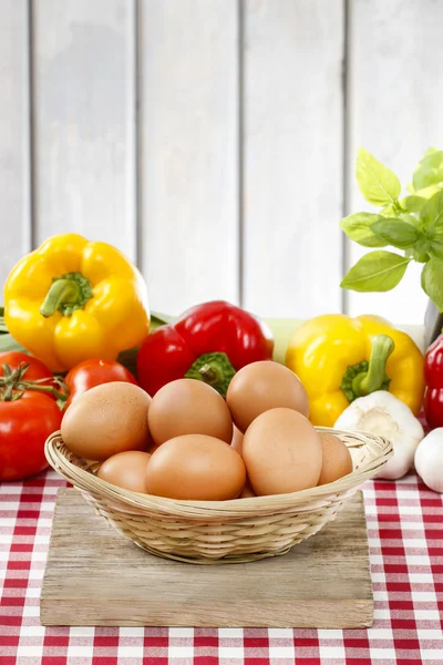 Stack of eggs, fresh vegetables in the background — Stock Photo, Image