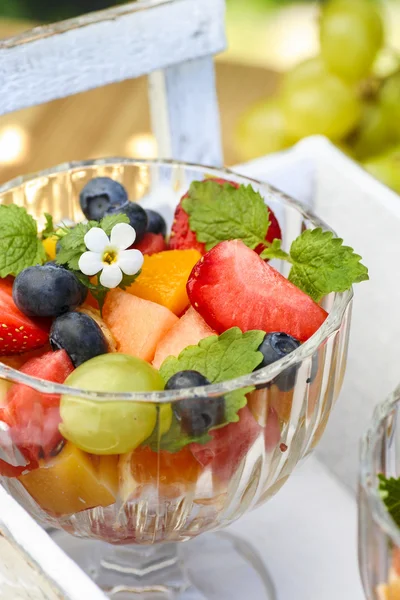 Salada de frutas frescas em um prato de vidro no jardim. Foco seletivo — Fotografia de Stock