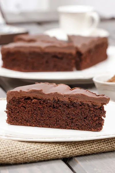 Chocolate cake on white plate, on hessian. — Stock Photo, Image
