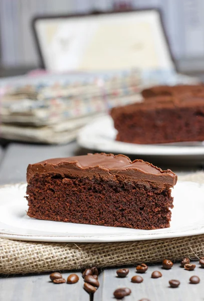 Chocolate cake on white plate, on hessian. Coffee beans — Stock Photo, Image