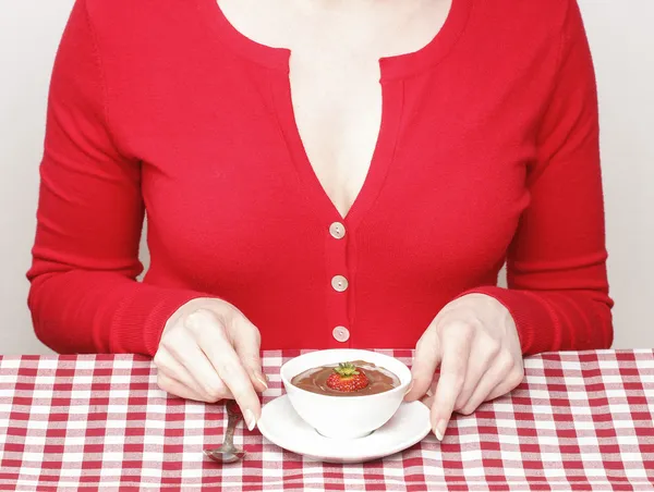 Mujer comiendo fondue de fresa de chocolate, sentada junto a la mesa — Foto de Stock