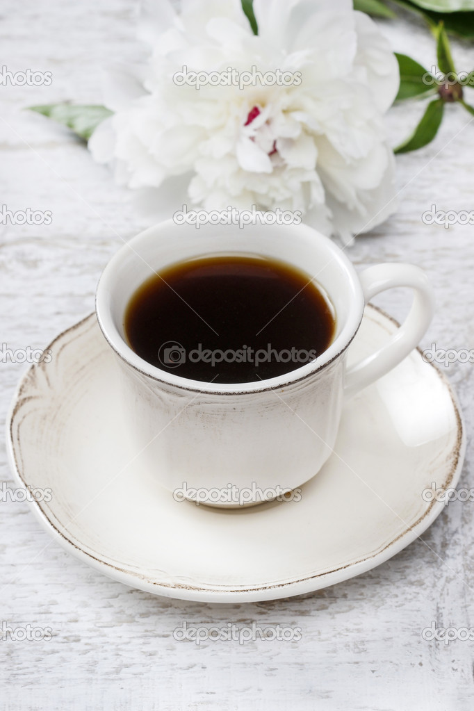 Cup of coffee and white peony on wooden rustic table