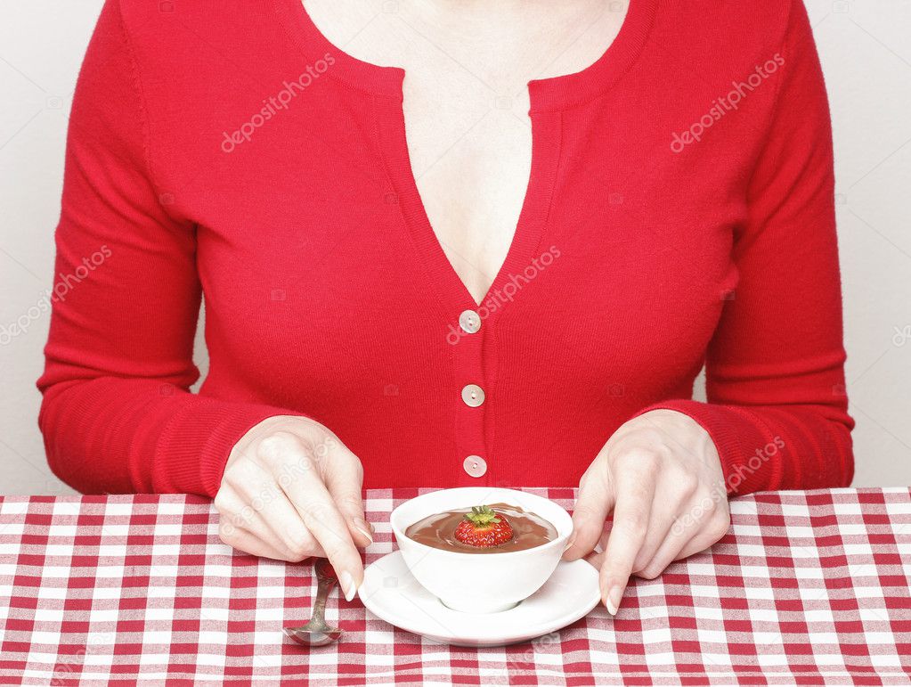 Woman eating chocolate strawberry fondue, sitting by the table