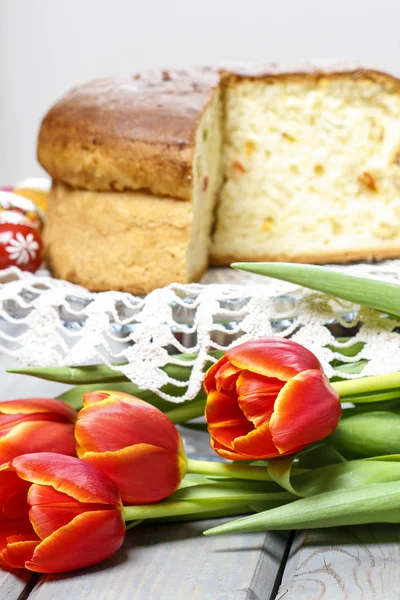 Red tulips in front of easter yeast cake. Selective focus — Stock Photo, Image