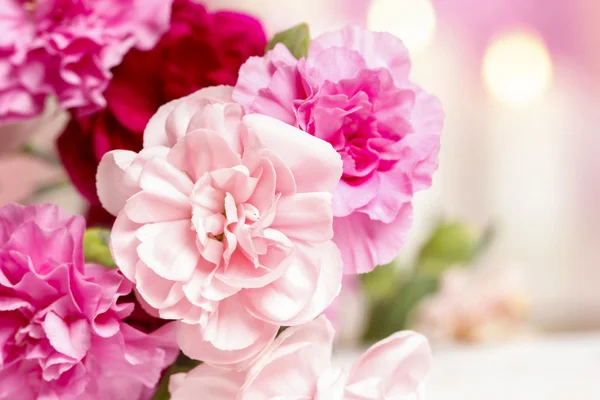 Bukett med rosa nejlikor blommor. ljus i bakgrunden — Stockfoto