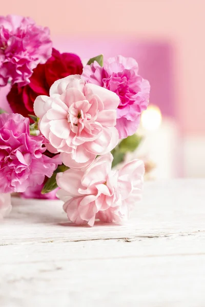 粉红色康乃馨花束。在背景中的蜡烛 — 图库照片