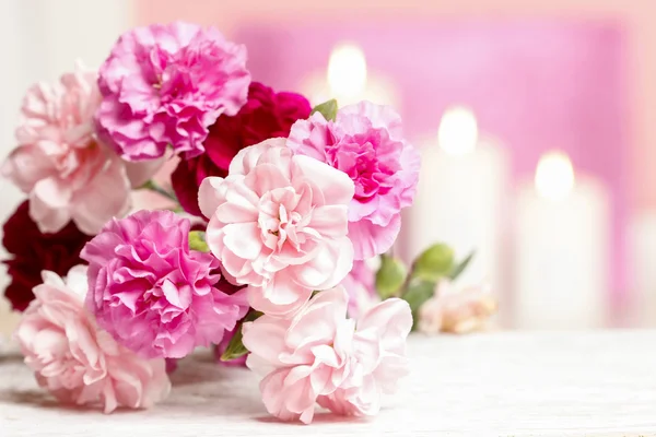 Bouquet of pink carnation flowers. Candles in the background — Stock Photo, Image