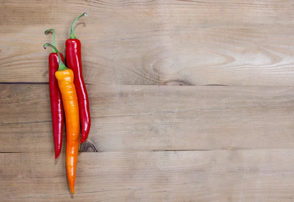 Rote Chilischoten auf altem Holztisch — Stockfoto