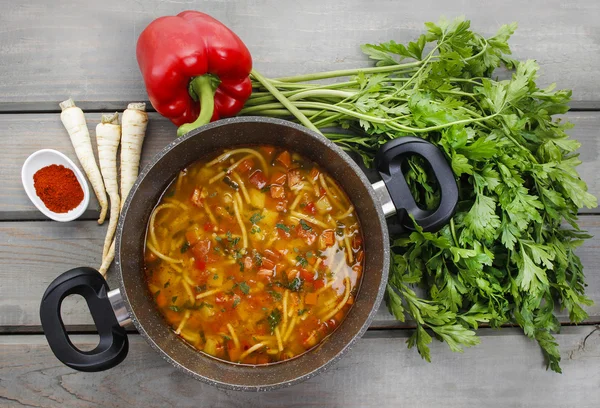 Bovenaanzicht op pot van tomatensoep en verse groenten op oud hout — Stockfoto