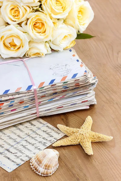 Pilha de cartas antigas e buquê de rosas amarelas pastel em madeira — Fotografia de Stock
