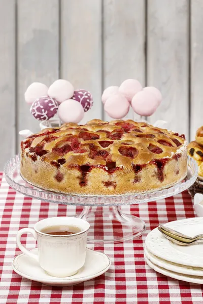 Strawberry pie on cake stand, checkered red table cloth