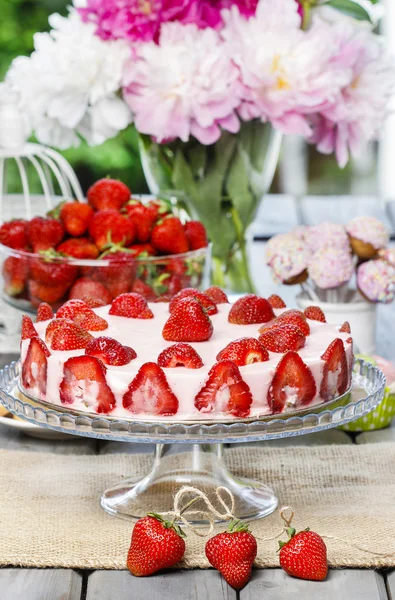 Gâteau aux fraises sur table rustique en bois dans un jardin d'été luxuriant — Photo