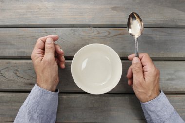 Aç adam onun yemek için boş kase içinde tahta masada bekliyor..