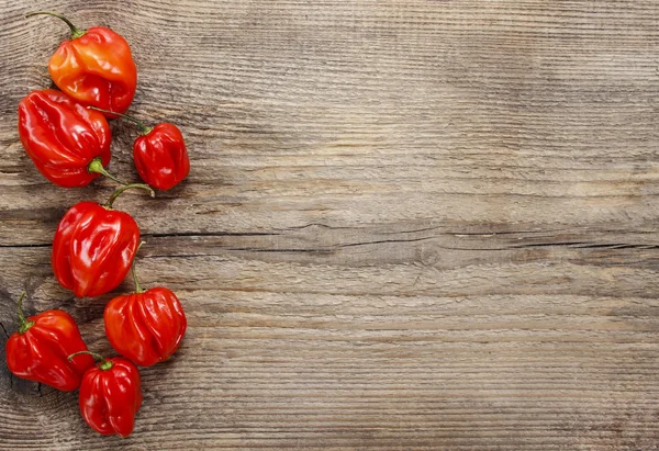 Red peppers on old wooden table. Blank board, copy space. — Stock Photo, Image