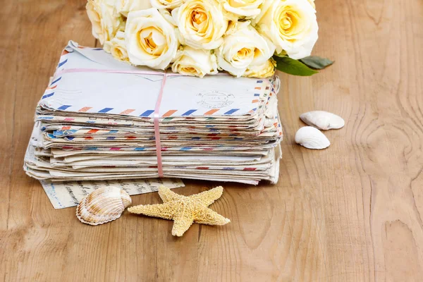 Stapelen van oude brieven en boeket van pastel gele rozen op hout — Stockfoto