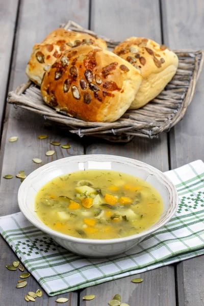 Vegetable soup on wooden table. Basket with fresh buns — Stock Photo, Image