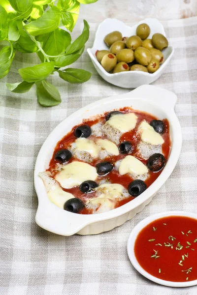 Queijo, molho de tomate e azeitonas pretas gratinadas na mesa quadriculada — Fotografia de Stock