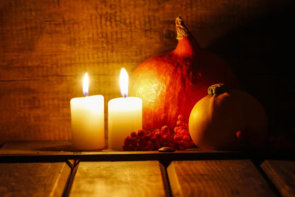 两个小蜡烛在旧的木制小屋。大的橙色南瓜 — 图库照片