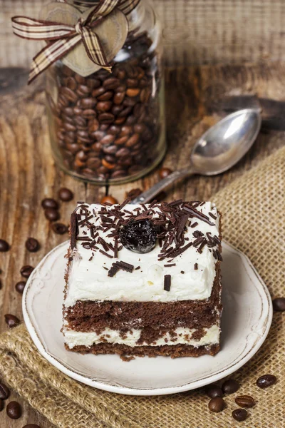 Pastel de chocolate y cereza. Café frijoles alrededor, espalda de madera —  Fotos de Stock