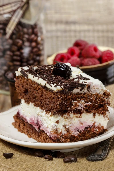 Pastel de chocolate y cereza. Café frijoles alrededor, fondo de madera — Foto de Stock