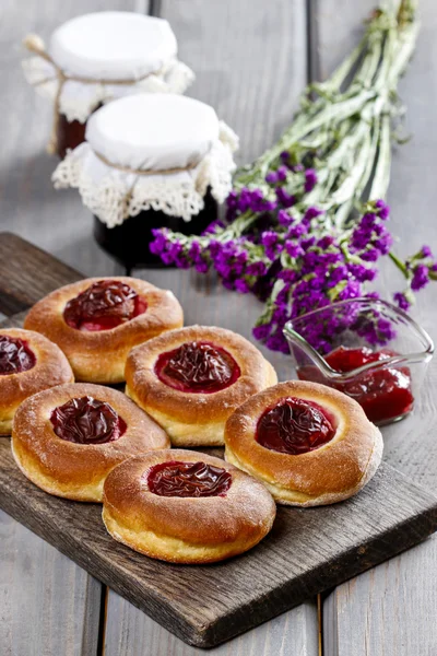 Runda bullar med plommon på träbord — Stockfoto