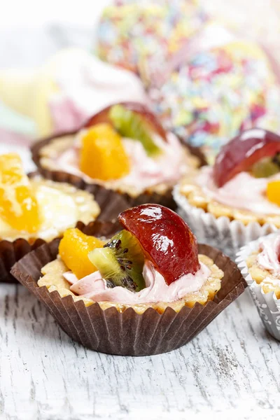 Kuchen mit frischen Früchten. Vielfalt an Süßigkeiten im Hintergrund — Stockfoto