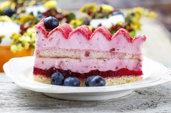 Gâteau en couche rose décoré de fruits frais sur une table en bois. Sel — Photo