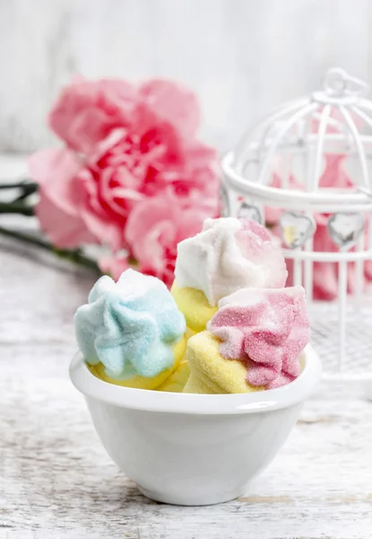 Marshmallows in white bowl among pink carnations — Stock Photo, Image