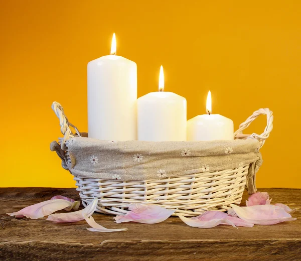 Candles in basket, orange background — Stock Photo, Image