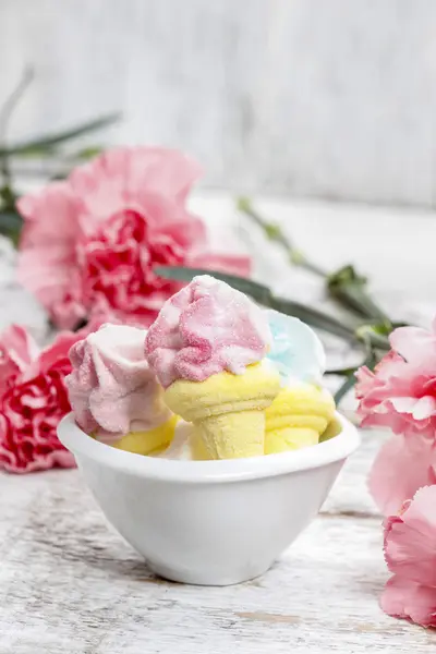 Marshmallows in ciotola bianca tra garofani rosa — Foto Stock