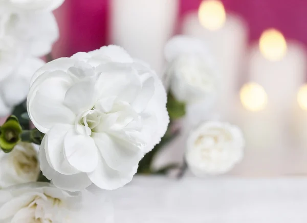 White carnation flowers. Candles in the background. Selective fo — Stock Photo, Image