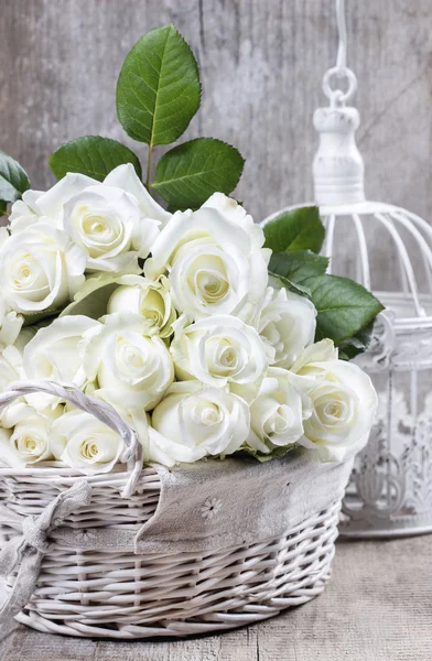 Ψάθινο καλάθι των άσπρων τριαντάφυλλων στο ρουστίκ ξύλινα τραπέζι — Φωτογραφία Αρχείου