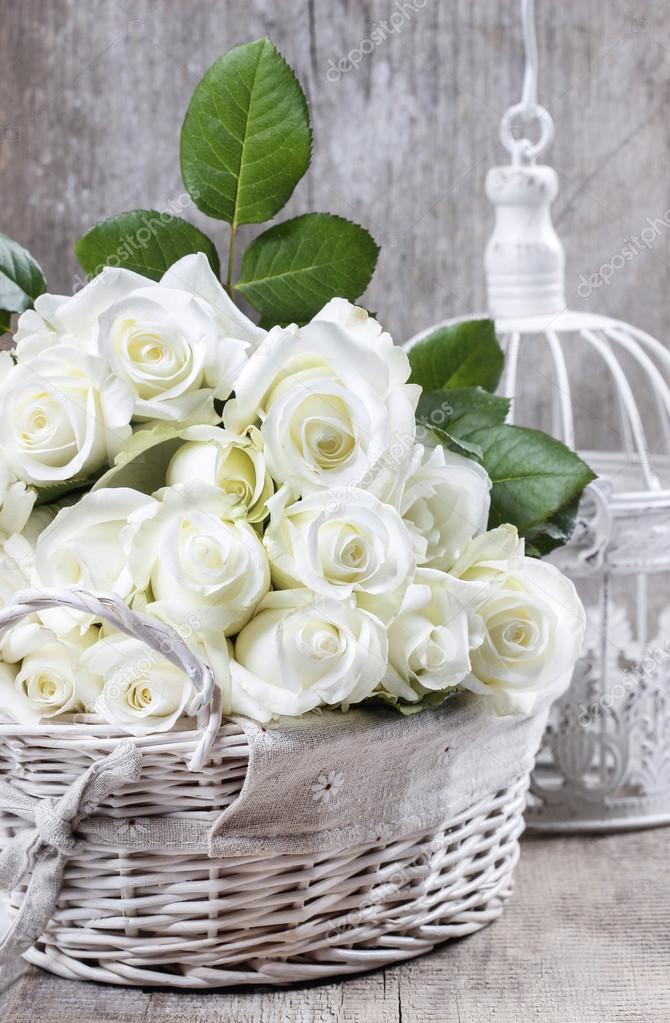 Wicker basket of white roses on rustic wooden table