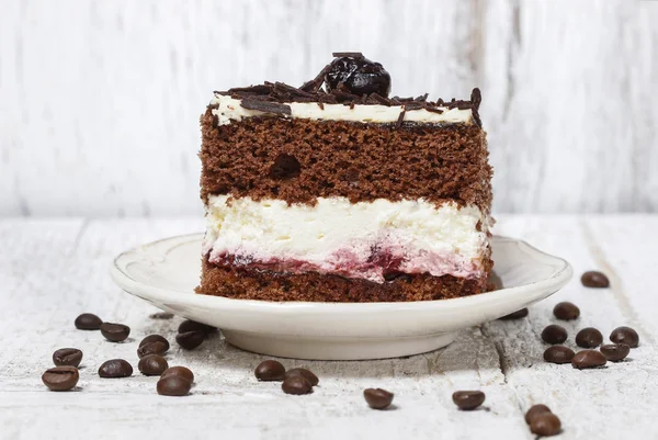 Chocolate and cherry cake. Coffee beans around, wooden back — Stock Photo, Image