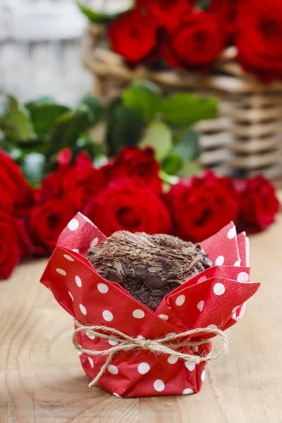 Chocolate muffins on party table. Basket of red roses in the bac — Stock Photo, Image