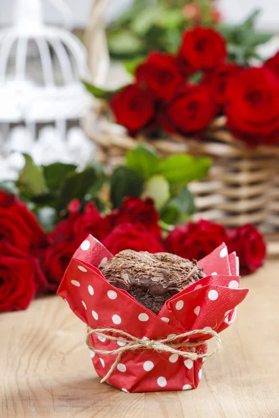Шоколадные кексы на праздничном столе. Корзина с красными розами в заливе — стоковое фото