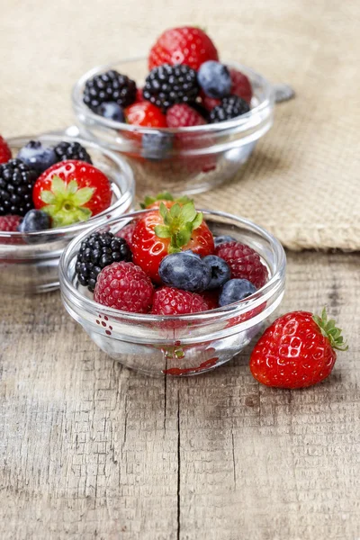 Fruitsalade in kleine transparante kommen op houten tafel — Stockfoto