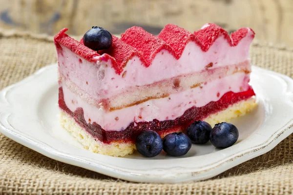 Gâteau en couche rose décoré de fruits frais sur table en bois — Photo