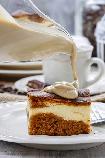 Pouring caramel sauce on piece of toffee and vanilla cake — Stock Photo, Image